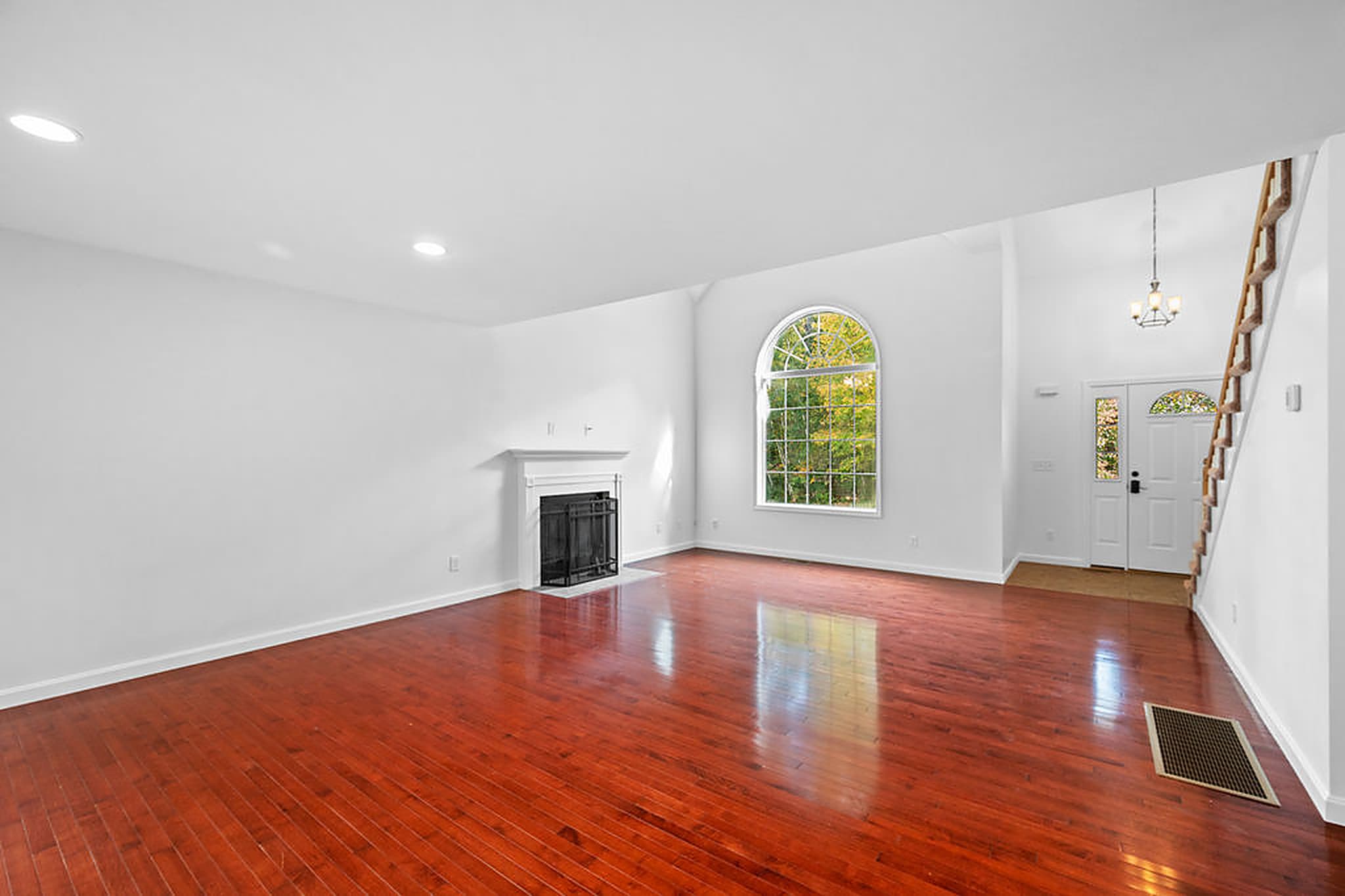 Two-story living room with the fireplace, arched window, and front entry